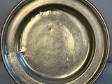 an antique silver plate on a stand on a white surface