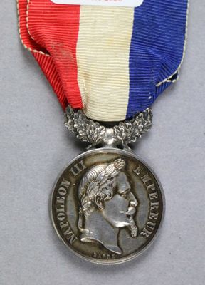 une photo représentant une médaille entourée d'un ruban, posée sur une table