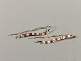 pair of gold tone earrings with red and white stones on them