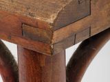 a small wooden table with a red cushion on it