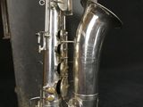 silver plated saxophone sitting on a black surface next to a case