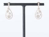 a pair of diamond earrings on a stand on a white background