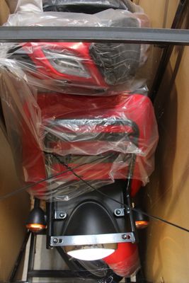 une moto rangée dans un carton, avec quelques sacs posés dessus