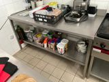 une cuisine équipée d'une cuisinière, d'un évier, d'une plaque de cuisson et d'autres éléments posés sur le plan de travail