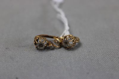 un gros plan sur une paire de boucles d'oreilles en or posées sur une surface grise