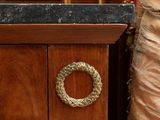 a wooden desk with a marble top and a gold ring on the drawer