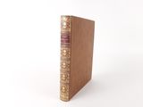 an old book sitting on top of a white table next to a white wall