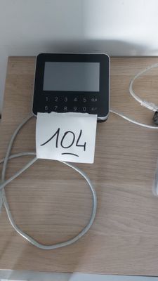 a small electronic device on a table with a note attached to it