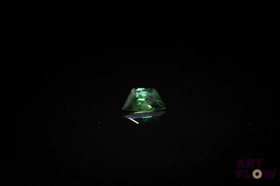 a close up of a green diamond on a black surface