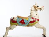 a toy horse that is standing on a white surface