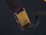 a gold watch with a brown leather band