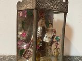 a small glass box with a miniature doll inside of it
