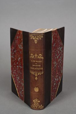 an old book with a red cover sitting on top of a table