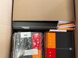 a cardboard box filled with notebooks and other office supplies