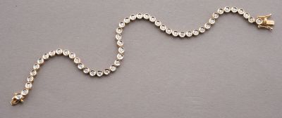chain of silver beads with a gold clasp on a gray surface