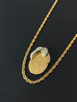 a close up of a gold necklace with a coin on it