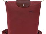 un sac à dos rouge avec une poignée marron et une sangle marron