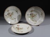 trois assiettes ornées de fleurs sont posées sur une table