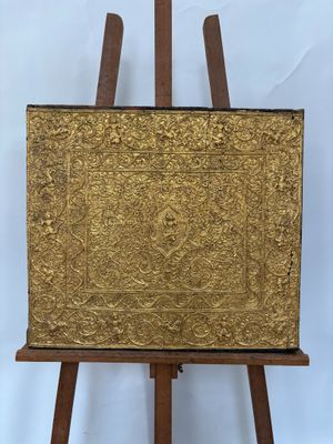 un vieux chevalet en bois surmonté d'un tableau doré