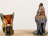 two stained glass vases sitting next to each other on a table