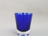 un verre bleu posé sur une surface blanche