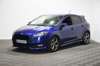 Une Ford Focus bleue est garée dans une pièce dont le sol est à carreaux.