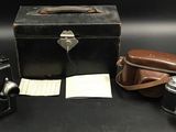 trois vieux appareils photo et une valise posés sur une table