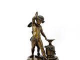 statue en bronze représentant un garçon avec une enclume, posée sur un socle