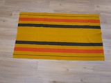 un gros plan sur un tapis rayé jaune et noir posé sur un parquet