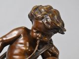 bronze statue of a boy with a pipe in his hand