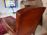 a brown leather chair sitting in front of a fireplace
