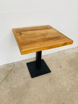 La table est en bois et possède un piètement en métal noir.