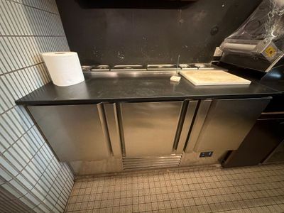 une cuisine équipée d'un évier et d'un plan de travail sur lequel est posé un rouleau de papier toilette