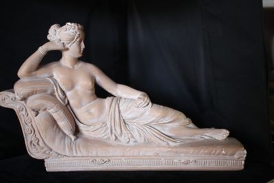 une statue représentant une femme assise sur un canapé