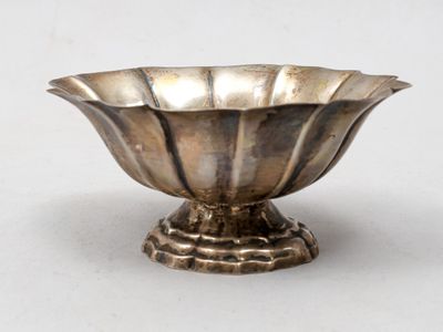 un bol en argent posé sur un socle, sur une surface blanche