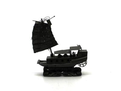 un bateau miniature avec une voile noire sur un fond blanc
