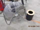 a metal fan sitting on the floor next to a roll of tape