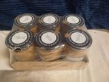 six jars of cookies in a wooden box on a table