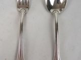 two silver spoons and a fork on a table
