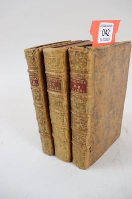 trois vieux livres sont empilés sur une surface blanche