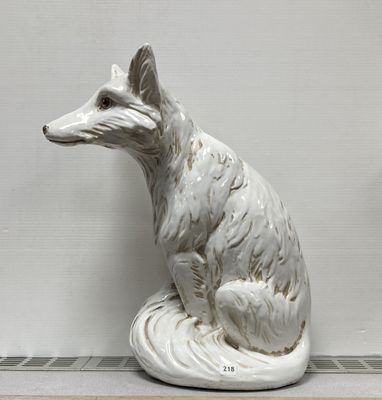 une statue blanche représentant un renard assis sur une table