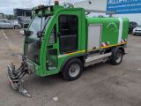 a green garbage truck parked in a parking lot