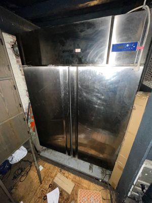 an image of a dirty kitchen with a refrigerator in it