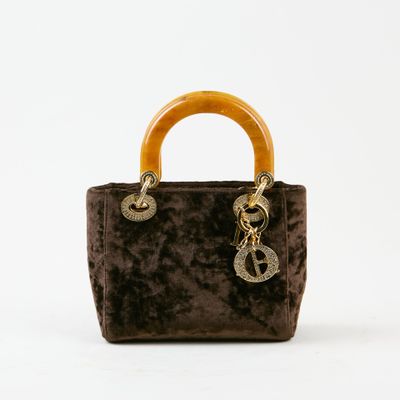 sac à main en velours marron avec une poignée en bois sur fond blanc