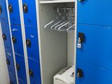 plusieurs casiers bleus dans une pièce, sur lesquels sont suspendus des vêtements