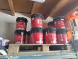 many cans of paint sitting on a pallet in a garage