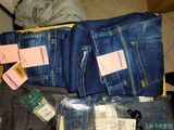several pairs of jeans are packed in a suitcase on the floor