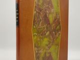 un vieux livre avec une couverture marron et une couverture verte et jaune