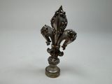 an antique silver fleuret on a pedestal with a white background