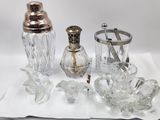 a silverware set on a white table with a silver spoon and a glass shaker